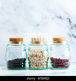 Diversi tipi di legumi in vasi di vetro con coperchi di sughero su un Sfondo marmo Foto Stock