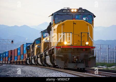 Una lunga fila di container di spedizione viene trasportata attraverso la Valle di Coachella interno in California da quattro locomotive diesel. le ferrovie nome è stato rimosso dalla parte frontale del locomotore Foto Stock