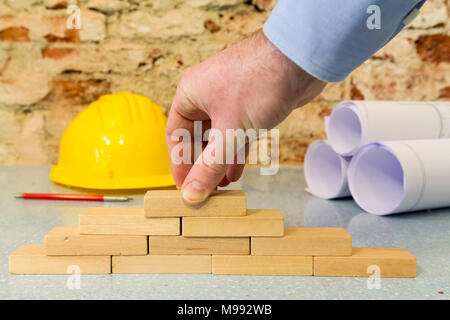 Impresa di costruzioni: la mano la costruzione di una parete in piccoli blocchi di legno Foto Stock