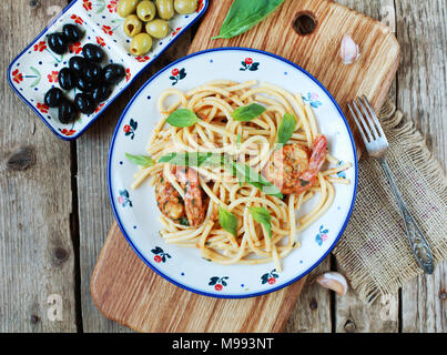 Pasta spaghetti con pesto rÐ¾ssÐ¾, gamberi, basilico e aglio su uno sfondo di legno. Messa a fuoco selettiva, vista dall'alto. Foto Stock