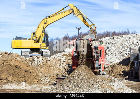 Trattore cingolato frantoio mobile escavatore e la frantumazione di cemento Foto Stock