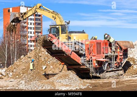 Frantumatore mobile cingolato e escavatore per frantumare edifici in cemento. Foto Stock