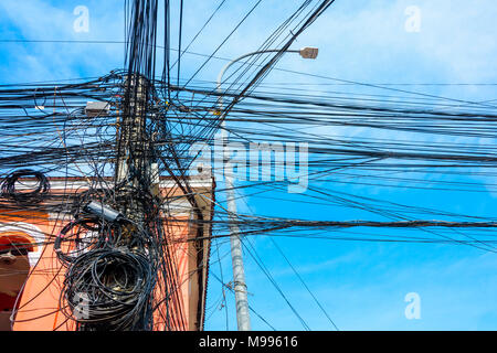 Enorme groviglio disordinato di decine di cavi elettrici alla sommità di un palo elettrico, Cambogia Foto Stock