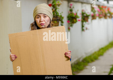 Vista esterna dei senzatetto donna tenendo alto vuoto segno di cartone Foto Stock