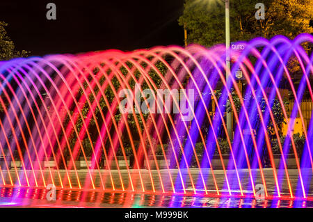 QUITO, ECUADOR- Febbraio 22, 2018: bella vista esterna di acqua colorata struttura di intrattenimento fontana, a lunga esposizione nella notte, con edifici dietro Foto Stock