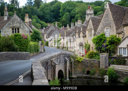 La strada e il ponte sul torrente dal e al villaggio di Castle Combe, Wiltshire, Inghilterra, Regno Unito Foto Stock