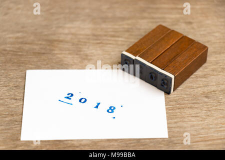 Testo blu 2018 sul libro bianco con il blocchetto di legno timbro su uno sfondo di legno Foto Stock