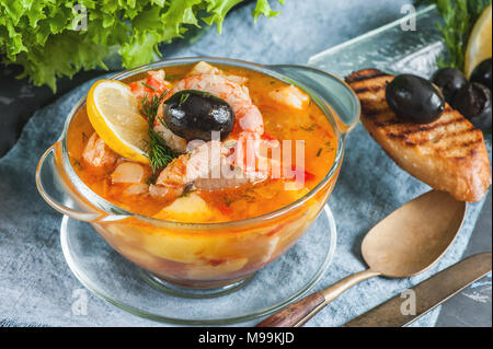 Il francese di una zuppa di pesce bouillabaisse con pesce e frutti di mare, il filetto di salmone e gamberetti con un sapore ricco, con crostini. Una deliziosa cena in una lastra di vetro trasparente. C Foto Stock