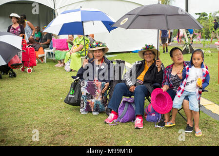 Un gruppo di donne il Niueano e ragazza riparo dalla pioggia sotto gli ombrelloni mentre si guarda un il Niueano display culturale presso il festival Pasifica ad Auckland.. Foto Stock