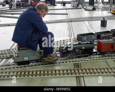 Il livello di massa 5' Manometro Mainline modello di associazione treno driver con un modello in scala del vapore serbatoio alimentato il motore essendo preparato per la corsa al NRM Foto Stock