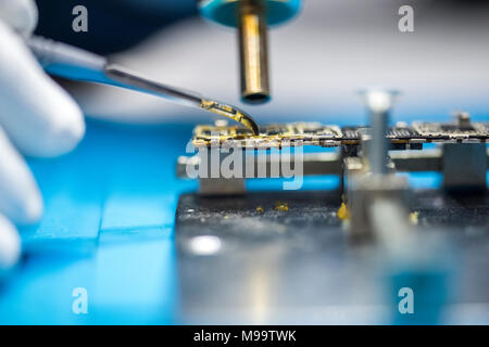 Le riparazioni di dispositivi elettronici, mani e gli attrezzi fissi, cellulari e computer Foto Stock