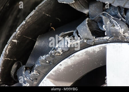 Chiudere i dettagli di una soffiata fuori pneumatico con in esploso, shredded e gomma danneggiati su un suv moderna automobile. Appartamento a basso profilo pneumatico su di un cerchione in lega, rip Foto Stock