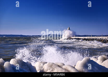 Faro di surgelati e pier su tempestoso giorno d'inverno Foto Stock