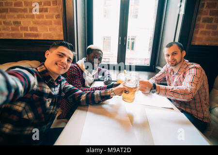 Allegro vecchi amici divertendosi prendendo selfie e bere birra nei pub Foto Stock