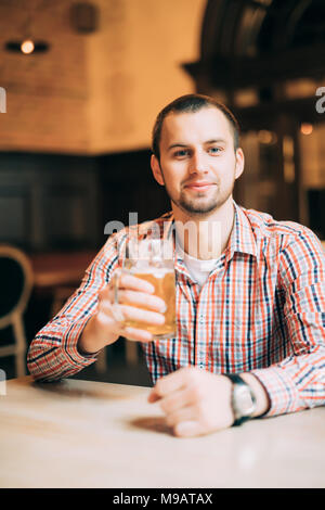 Bel giovane bere birra chiara in un pub Foto Stock