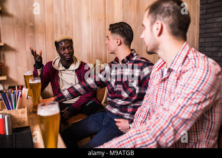 Allegro vecchi amici divertendosi e bere birra presso il bar contatore nel pub. Foto Stock