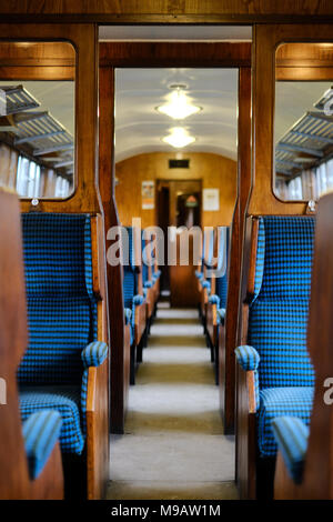 Interno di un carrello che porta i turisti alla Worth Valley Railway nel West Yorkshire che mostra la vecchia costruzione in legno e imbottita blu posti a sedere Foto Stock