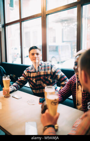 La gente, uomini, di svago, di amicizia e di celebrazione concetto - happy amici maschi a bere birra e tintinnanti bicchieri al bar o pub Foto Stock