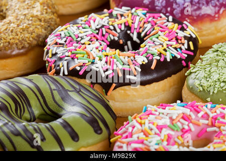 Close up colorato e deliziose ciambelle un pasto preferito per la prima colazione Foto Stock