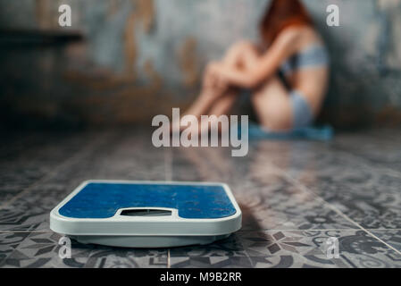 Anoressica donna seduta sul pavimento, la perdita di peso Foto Stock