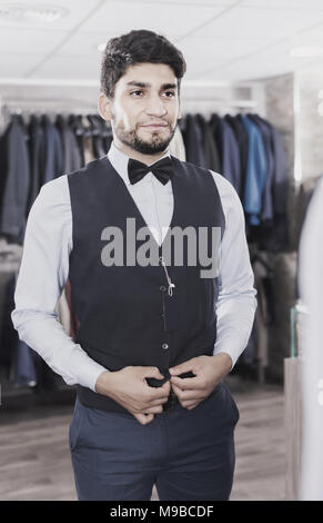 Ragazzo sta cercando sull'immagine scelta di fronte allo specchio in uomini shop. Foto Stock