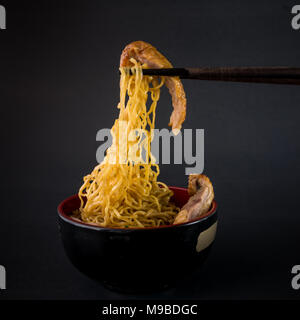 Bacchette e anatra arrosto a base di noodle su sfondo nero Foto Stock