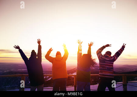 Happy amici con le mani alzate al tramonto Foto Stock