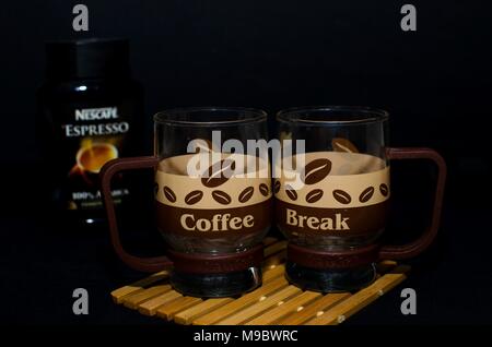 Nsi,Serbia, Marzo 13, 2018:due bicchieri insolito con il coffee design dicendo pausa caffè con sfocato nescafe vasetto in vetro in background sul nero, studio Foto Stock
