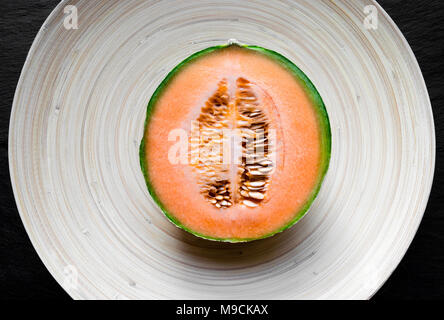 Tagliare ted nella metà del melone Hami frutti sulla piastra di bambù Foto Stock