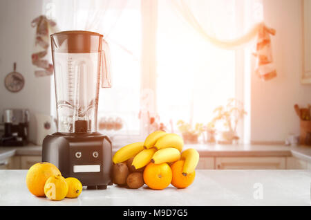 Cibo di metallo blender close-up con fresca tropico Esotici frutti accanto ad essa su cucina sfondo con spazio vuoto. Frullatore e tavolo in legno in cucina. Su Foto Stock