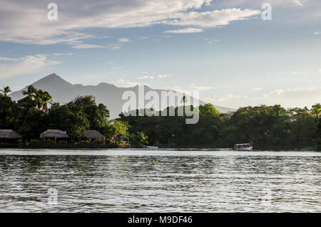 Barca passando attraverso gli isolotti di Granada con il vulcano Mombacho in background - Nicaragua america centrale Foto Stock