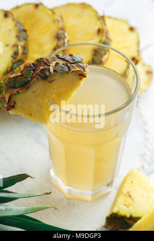 Ananas spremuta fresca in vetro su un tavolo in legno su cemento grigio sfondo Foto Stock