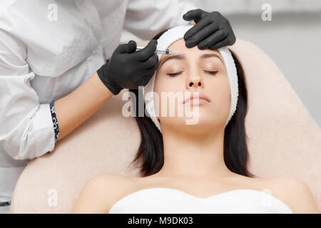 Specialista di Cosmetologia dando iniezione di sollevamento alla bella donna. Foto Stock