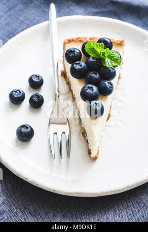 Cheesecake con mirtilli freschi sulla piastra bianca, il fuoco selettivo composizione verticale Foto Stock