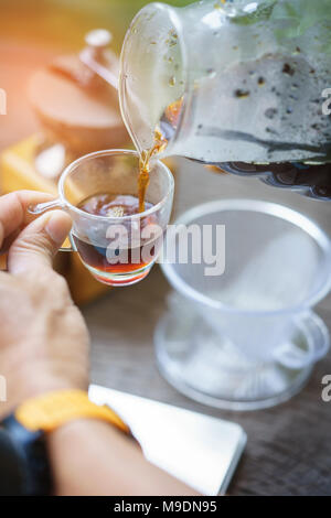 Inquadratura ravvicinata del barista mani versando il caffè per una tazza di caffè. Messa a fuoco selettiva su mani tazza di caffè. Foto Stock