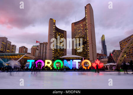 Toronto City Hall, Nathan Phillips Square in inverno, pista di pattinaggio sul ghiaccio al crepuscolo, insegna di Toronto, persone nel centro di Toronto, Ontario, Canada. Foto Stock