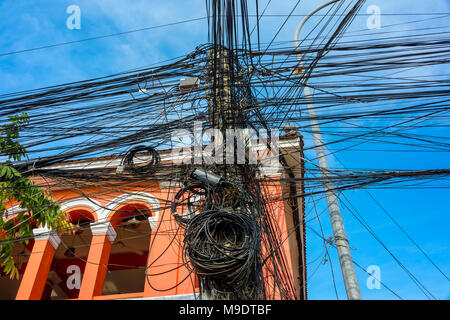 Enorme groviglio disordinato di decine di cavi elettrici alla sommità di un palo elettrico, Cambogia Foto Stock