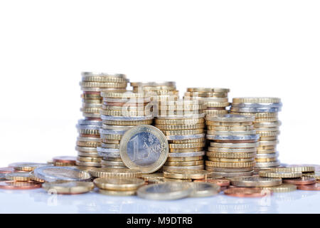 Un euro moneta si trova di fronte a più monete poste in colonne isolato su bianco e con la riflessione in terra. Foto Stock