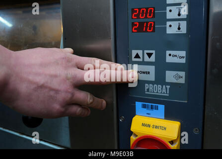 Presso la pasticceria: baker la mano premendo un pulsante di alimentazione su un pannello di controllo di un forno elettrico. Marzo 21, 2018. Brovary, Ucraina Foto Stock