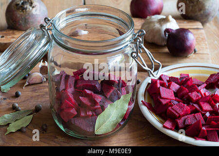 Ingredienti per la preparazione di barbabietole kvass (fermentati bietole) in un vasetto di vetro - fette di barbabietole rosse, cipolle, aglio, alloro, pepe della Giamaica Foto Stock