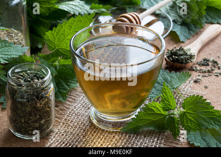 Una tazza di tè di ortica con fresco e asciutto di ortiche in background Foto Stock