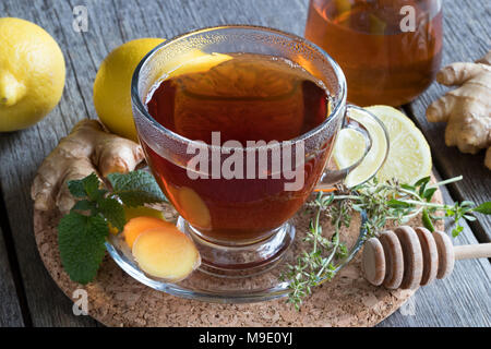 Una tazza di tè allo zenzero, limone, erbe e miele Foto Stock