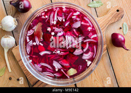 Preparazione di barbabietole kvass (fermentati barbabietole rosse) - Bietole, cipolle, aglio, alloro e il pepe della Giamaica in una ciotola Foto Stock