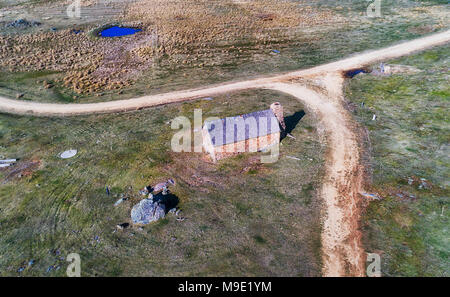 Abbandonato casale in pietra capanna Crackenback vicino a Thredbo valle delle montagne innevate, Australia. Veduta aerea della casa e nelle vicinanze di strada sterrata w Foto Stock