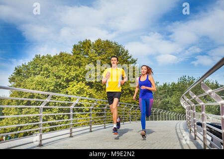 Coppia sportiva in esecuzione attraverso un ponte in estate Foto Stock