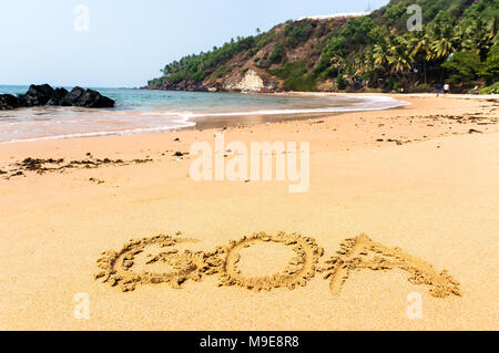 L'iscrizione Goa su di una spiaggia di sabbia contro il blu del mare e le acque turchesi e le onde Foto Stock