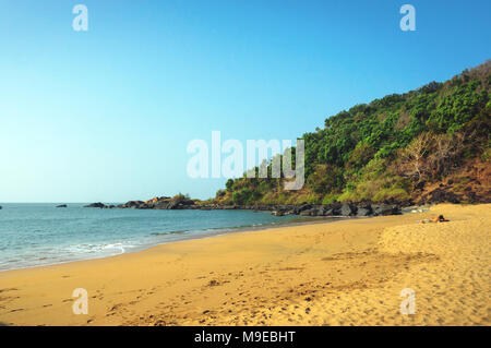 La ripida costa rocciosa con il blu del mare e le onde che si infrangono sulle rocce. Gokarna India Foto Stock