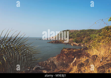 La ripida costa rocciosa con il blu del mare e le onde che si infrangono sulle rocce. Gokarna India Foto Stock