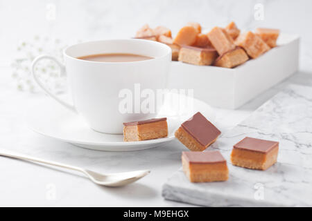 Caramello e biscotto morsi shortcake dessert su scheda di marmo e Coffee Cup Foto Stock