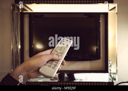 Tv bianco telecomando in mano Foto Stock